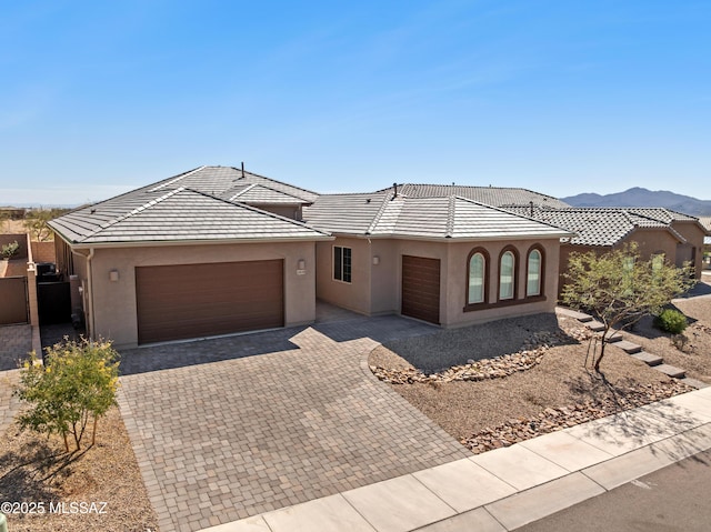 view of front of property featuring a garage, decorative driveway, a tile roof, and stucco siding