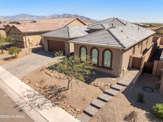 view of front of home with decorative driveway, a mountain view, and stucco siding