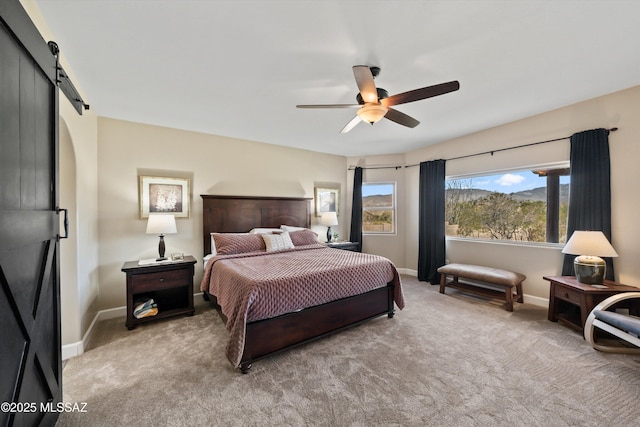 carpeted bedroom with a ceiling fan, baseboards, and a barn door