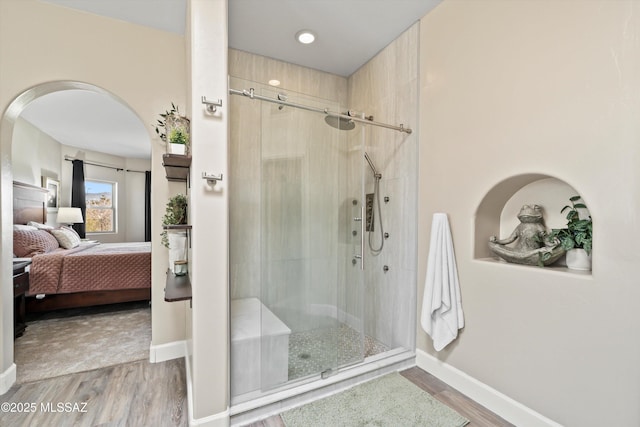 ensuite bathroom with ensuite bathroom, a stall shower, and wood finished floors