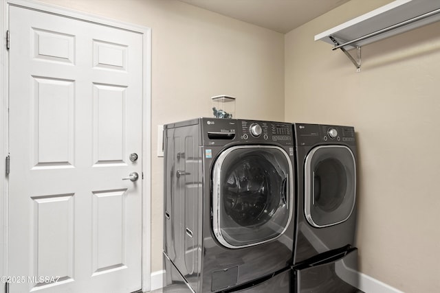 clothes washing area with washing machine and dryer, laundry area, and baseboards