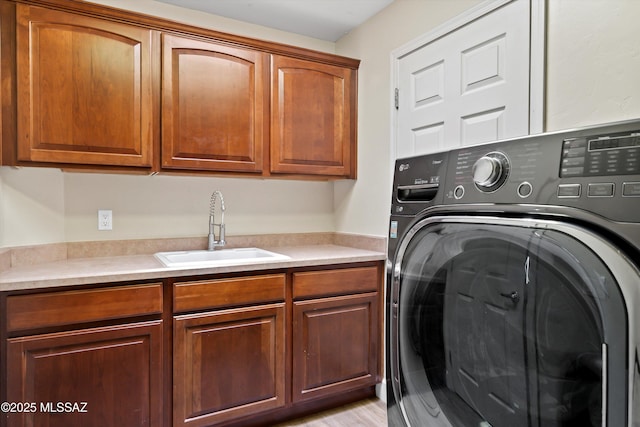 washroom with washer / dryer, cabinet space, and a sink