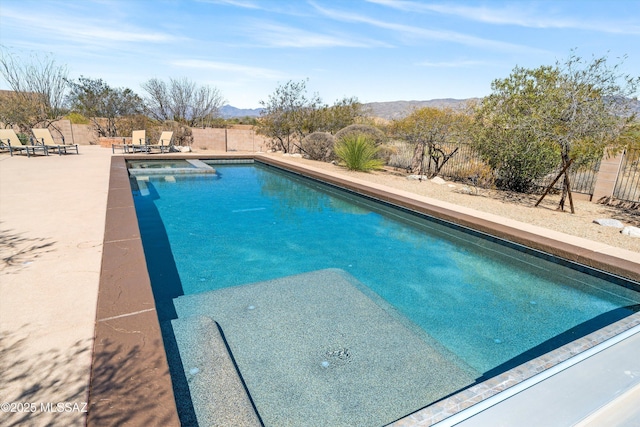 view of pool featuring a mountain view, a patio area, a fenced backyard, and a pool with connected hot tub