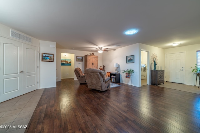 living room with washer / clothes dryer, visible vents, a ceiling fan, wood finished floors, and baseboards