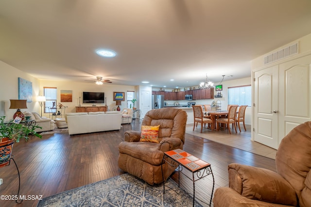 living area featuring ceiling fan with notable chandelier, wood finished floors, and visible vents