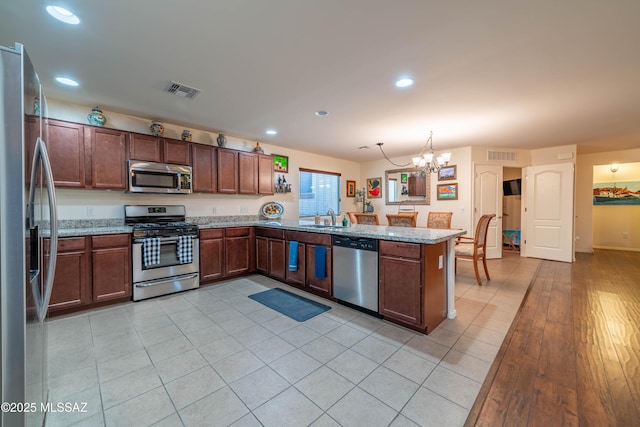 kitchen featuring appliances with stainless steel finishes, visible vents, a sink, and a peninsula