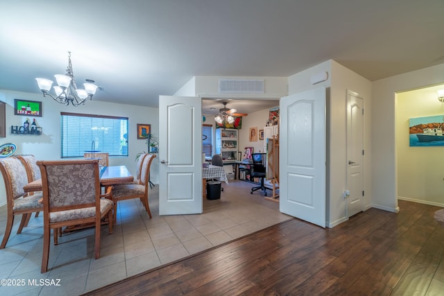 dining space with ceiling fan with notable chandelier, visible vents, baseboards, and wood finished floors