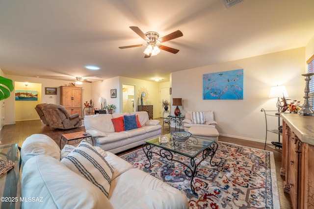 living area with a ceiling fan, visible vents, baseboards, and wood finished floors