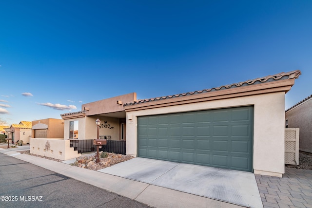 view of front of home with an attached garage, fence, driveway, a tiled roof, and stucco siding