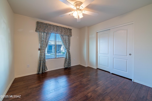 unfurnished bedroom featuring ceiling fan, a closet, dark wood finished floors, and baseboards