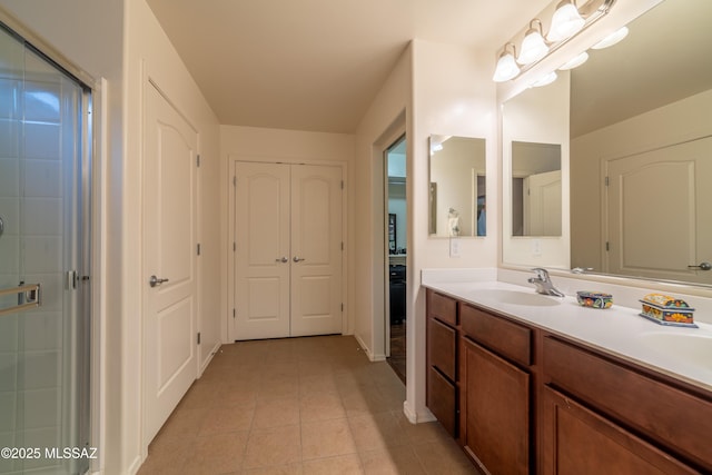 bathroom featuring tile patterned flooring, a shower with door, a sink, and double vanity