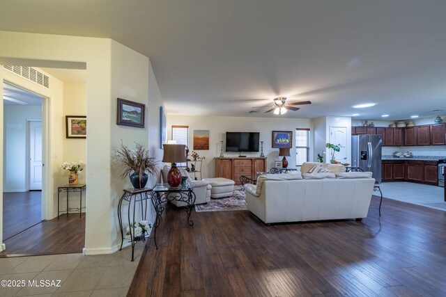 living room featuring a ceiling fan, baseboards, visible vents, and wood finished floors