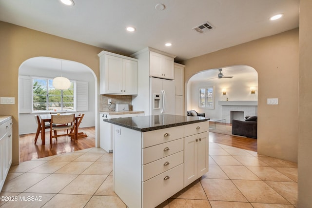 kitchen featuring light tile patterned floors, visible vents, decorative backsplash, ceiling fan, and white fridge with ice dispenser