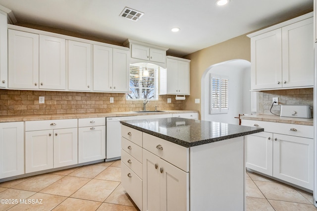 kitchen with light tile patterned floors, arched walkways, visible vents, and dishwasher