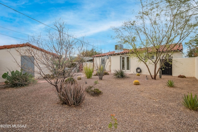 rear view of property with french doors, fence, and stucco siding