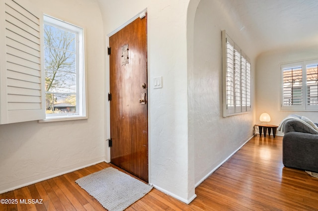 entryway with arched walkways, a textured wall, and hardwood / wood-style floors