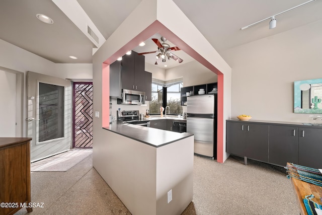 kitchen with a peninsula, recessed lighting, a sink, stainless steel appliances, and light speckled floor