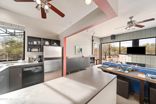 kitchen featuring open shelves, freestanding refrigerator, a sink, black dishwasher, and open floor plan