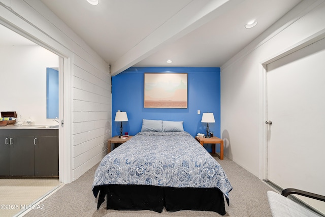 carpeted bedroom featuring beam ceiling, recessed lighting, and a sink