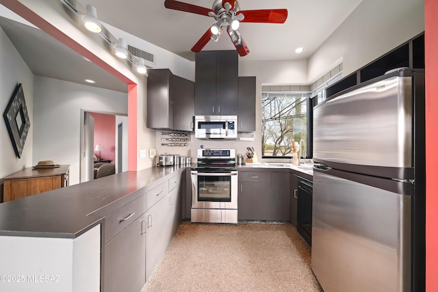 kitchen with visible vents, a sink, light speckled floor, stainless steel appliances, and a peninsula