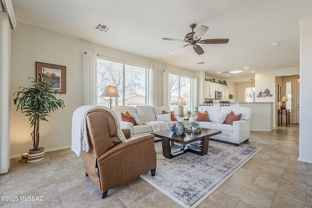 living room featuring baseboards, visible vents, and a ceiling fan