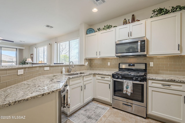 kitchen with stainless steel appliances, a sink, visible vents, and decorative backsplash