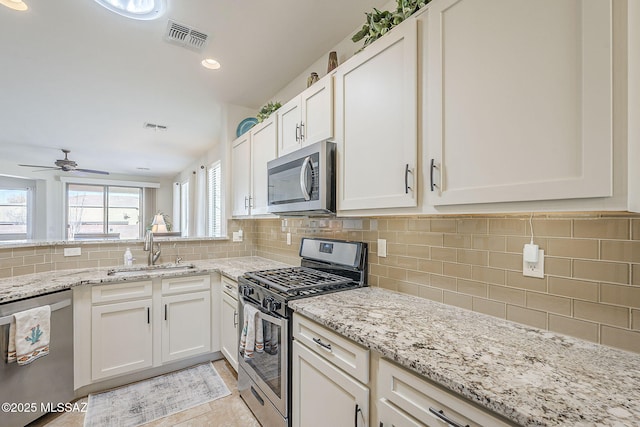 kitchen with stainless steel appliances, a sink, visible vents, white cabinets, and backsplash