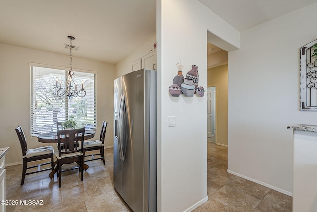 kitchen with stainless steel fridge with ice dispenser, visible vents, an inviting chandelier, white cabinetry, and baseboards