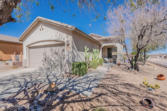 view of front facade with driveway, an attached garage, fence, and stucco siding