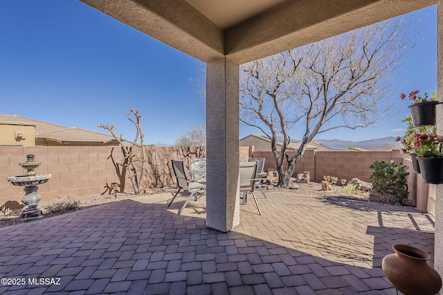 view of patio / terrace with a fenced backyard, a mountain view, and outdoor dining space