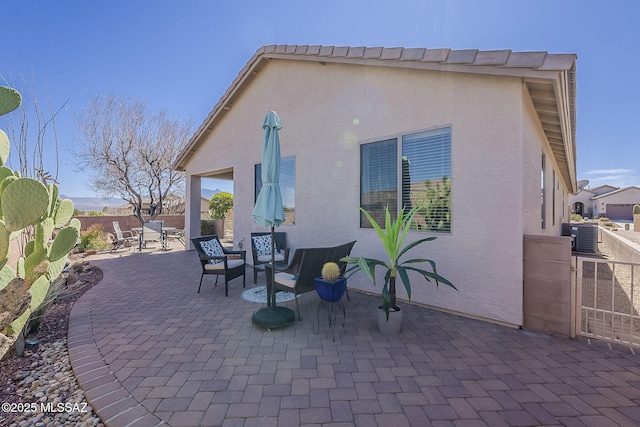 rear view of property with a patio area, fence, and stucco siding