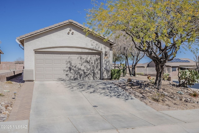 view of front of property with driveway, fence, an attached garage, and stucco siding