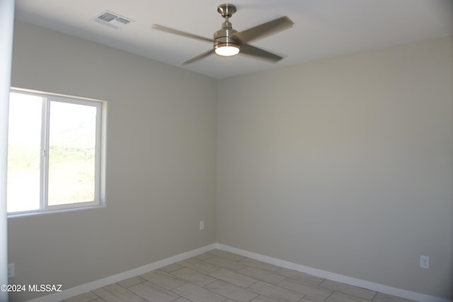 spare room with a ceiling fan, visible vents, and baseboards