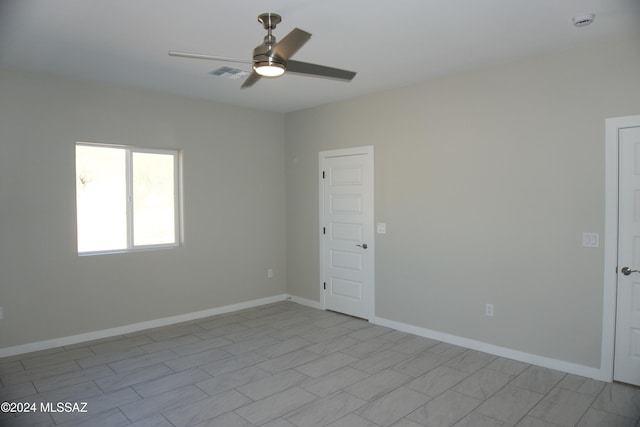 unfurnished room with a ceiling fan, visible vents, and baseboards