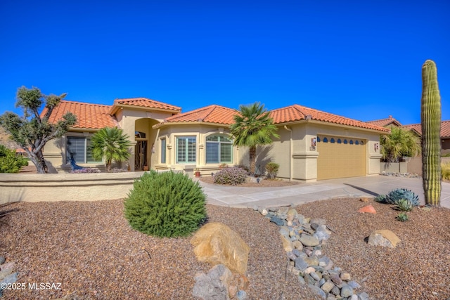 mediterranean / spanish home featuring an attached garage, driveway, a tile roof, and stucco siding