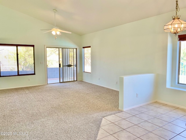 empty room featuring lofted ceiling, light colored carpet, plenty of natural light, and light tile patterned floors