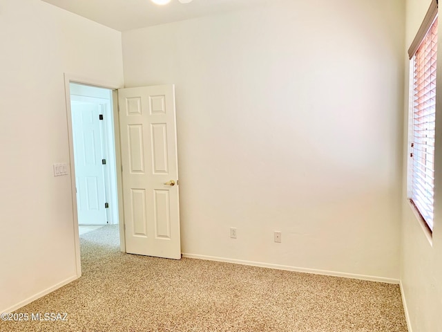 empty room featuring baseboards and light colored carpet