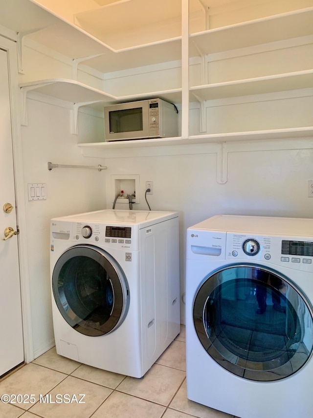 laundry area featuring light tile patterned floors, laundry area, and washing machine and clothes dryer