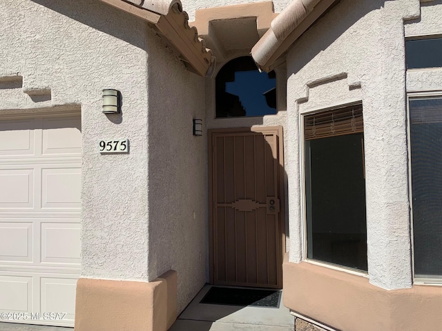 entrance to property featuring a garage and stucco siding