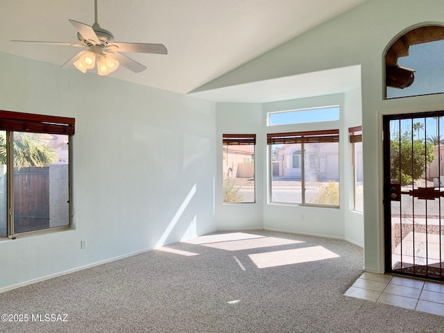 carpeted spare room with tile patterned flooring, high vaulted ceiling, ceiling fan, and baseboards