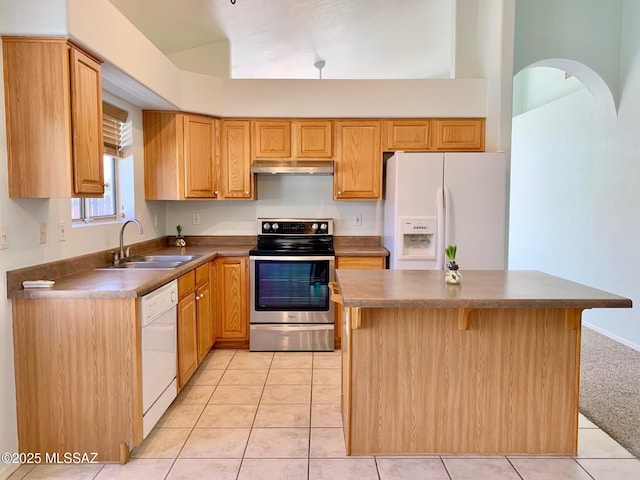 kitchen with light tile patterned floors, under cabinet range hood, white appliances, a sink, and dark countertops