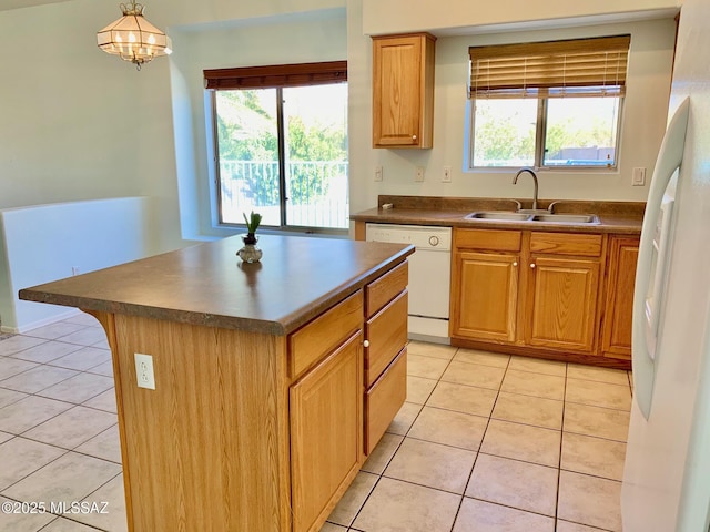 kitchen with dark countertops, light tile patterned flooring, a sink, a healthy amount of sunlight, and white appliances