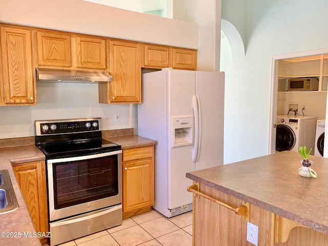 kitchen with light tile patterned floors, electric range, white refrigerator with ice dispenser, separate washer and dryer, and wall chimney exhaust hood