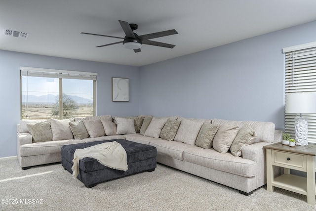 carpeted living area with baseboards, visible vents, and ceiling fan