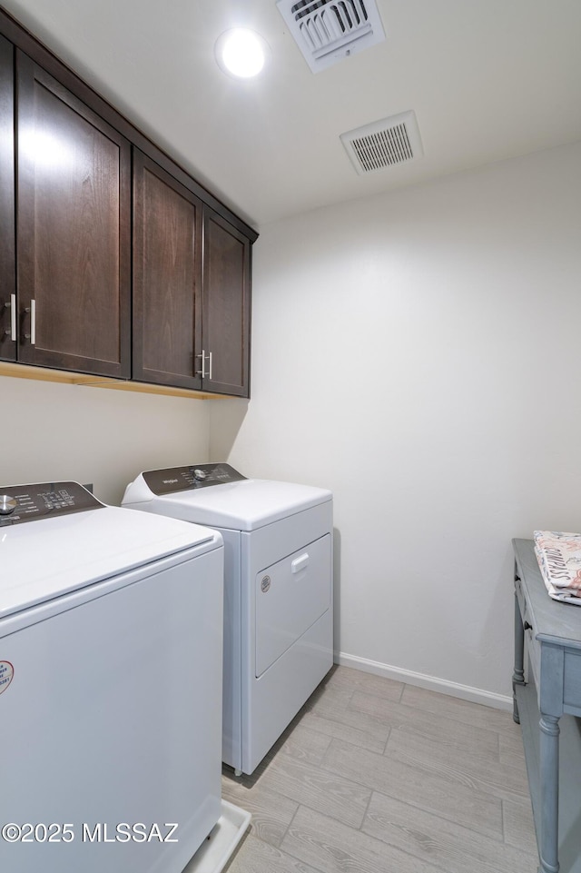 laundry area featuring cabinet space, separate washer and dryer, visible vents, and baseboards