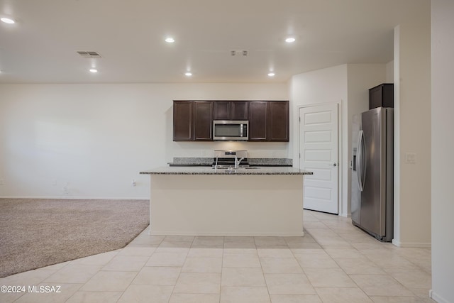 kitchen featuring visible vents, light colored carpet, appliances with stainless steel finishes, dark brown cabinets, and a sink