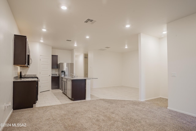 kitchen featuring open floor plan, dark brown cabinets, visible vents, and light colored carpet