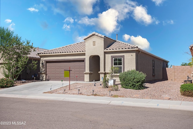 mediterranean / spanish home featuring a garage, fence, a tile roof, concrete driveway, and stucco siding