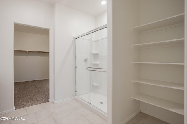 full bathroom featuring a stall shower, a walk in closet, and baseboards