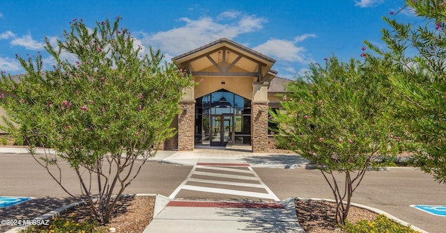 view of exterior entry with stone siding, french doors, and stucco siding